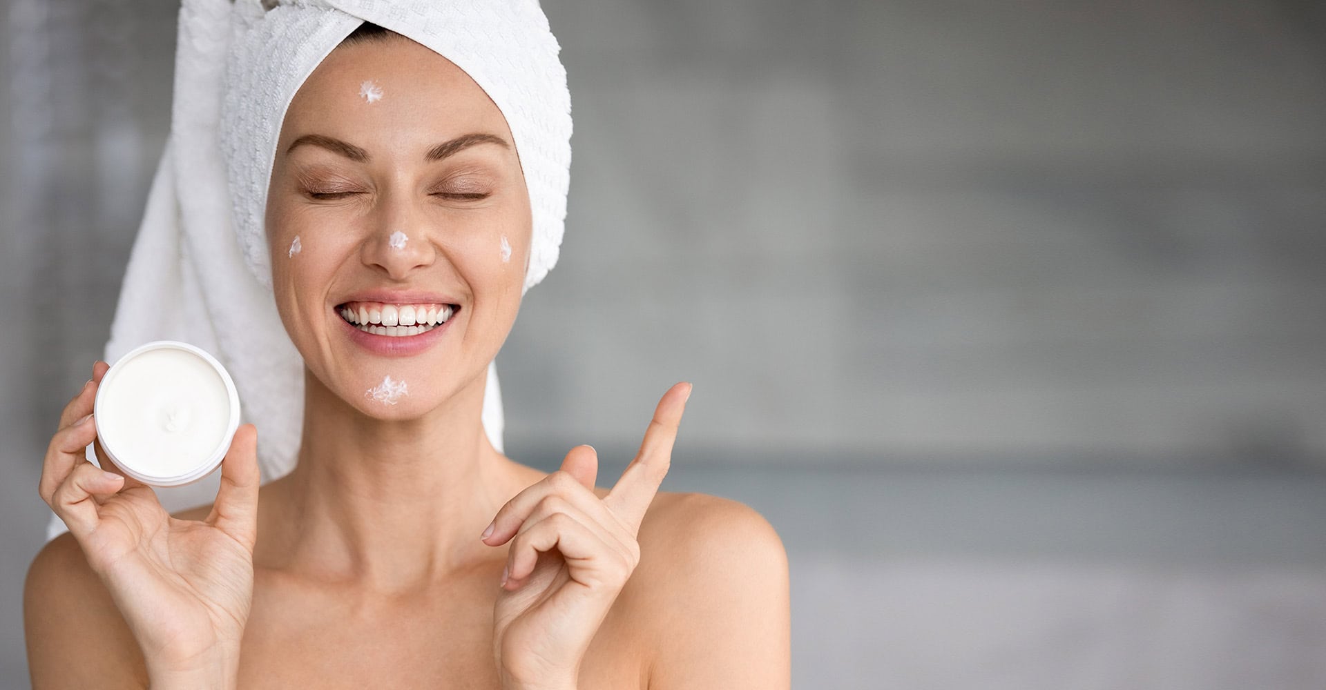 Smiling woman holding skincare cream